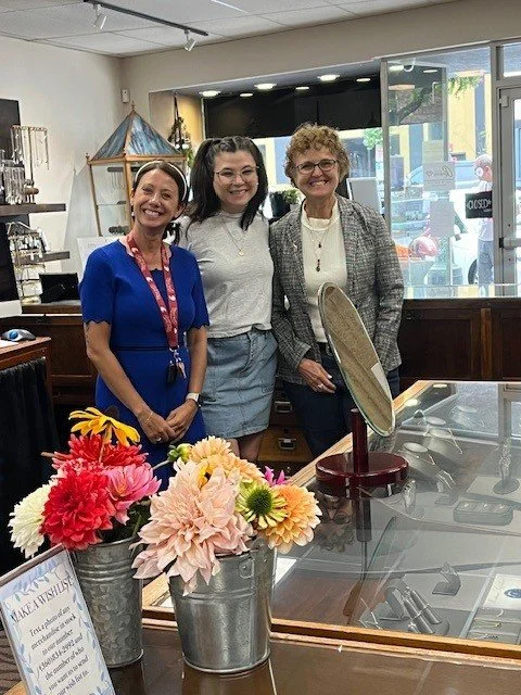Three smiling Four Gals Foundation team members standing inside a local Camas business during the Art and Wine Walk.
