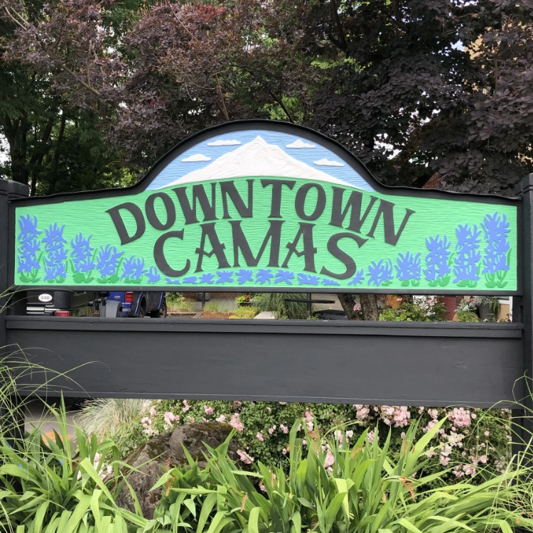 A decorative "Downtown Camas" welcome sign featuring Mt. Hood and camas lilies, home of the Art and Wine Walk.