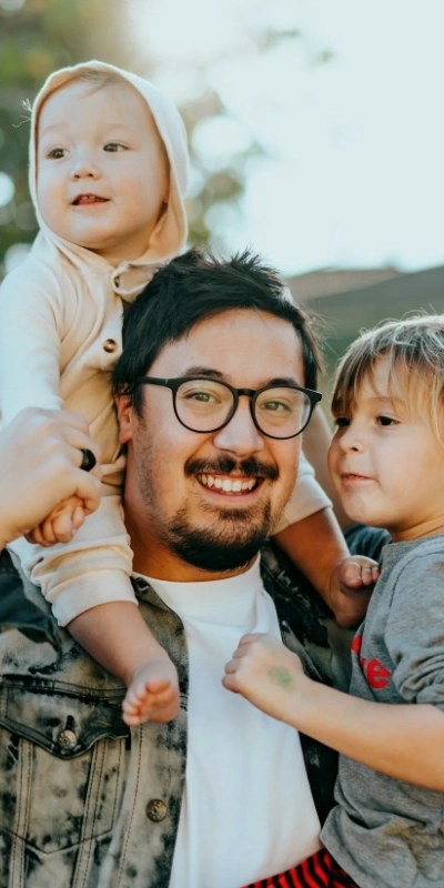 Father holding his two small children outdoors in Camas, WA, part of the Camas Students and Families Foundation fundraiser community.