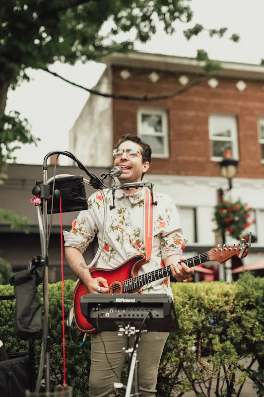 A local musician playing electric guitar and singing for the crowd at the annual Camas Art and Wine Walk in Washington.