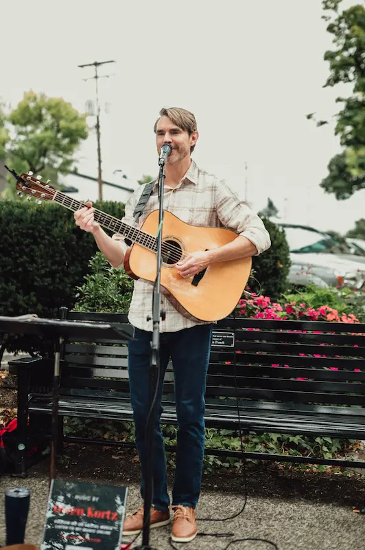 A live musical performance by a guitarist entertaining the crowd during the annual Camas Art and Wine Walk festival.