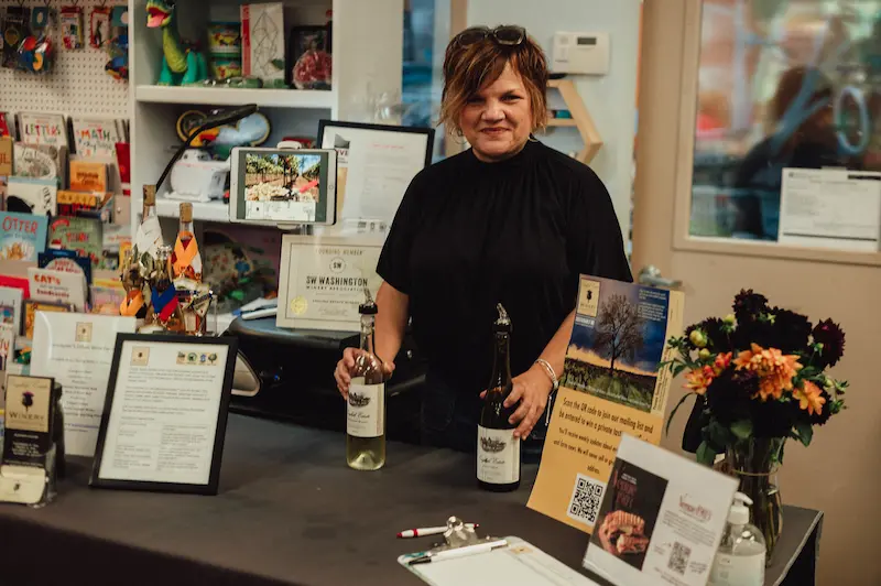 A friendly wine pourer representing the SW Washington Winery Association at a tasting station in Downtown Camas.