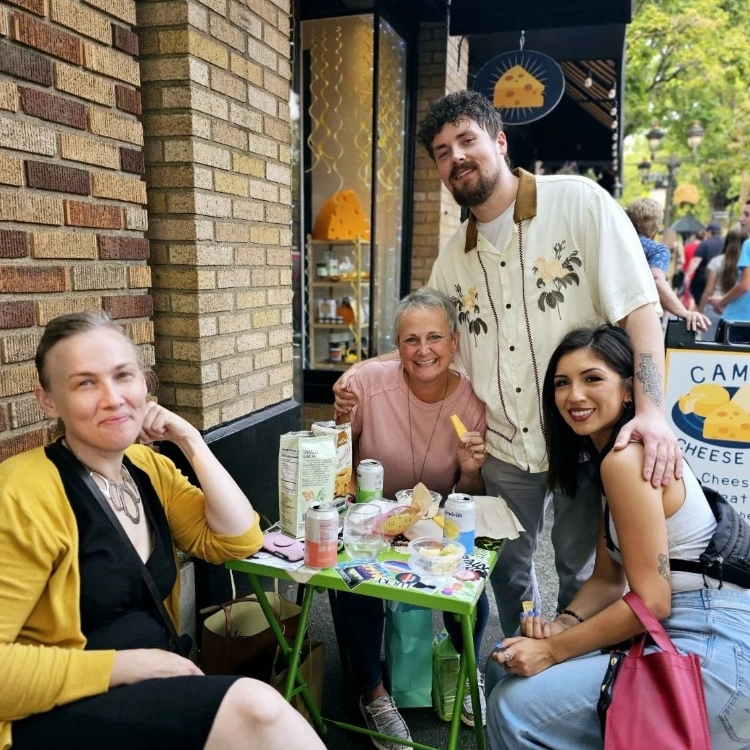A group of attendees and volunteers enjoying cheese pairings at an outdoor table in Downtown Camas, WA.